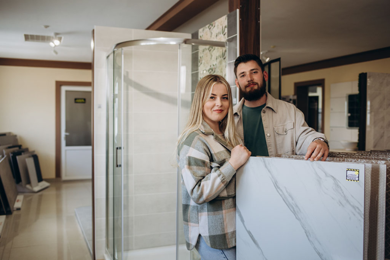 Beautiful young couple choosing ceramic tiles for their house repairment in the building shop