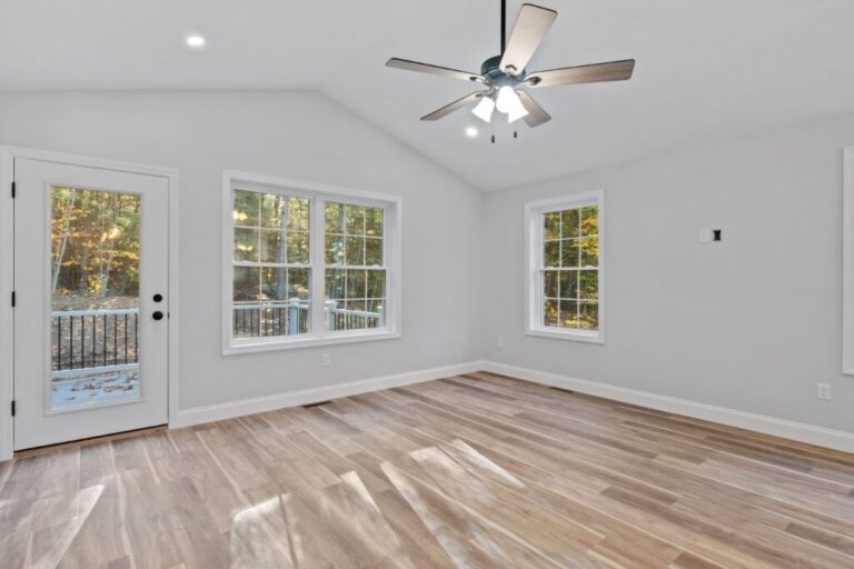 Indoor view of a newly constructed house with white walls, broad windows and a ceiling fan